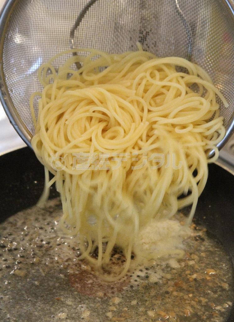 チーズと黒こしょうのパスタ（作り方２）＿＿スパゲティがゆであがる３０秒前に火にかけ、パルメザンチーズ、粗びき黒こしょうを加え、さっと混ぜ、（作り方１：調理したニンニクソース）にスパゲティ、スパゲティのゆで汁をさらにもう１杯加えてあえる。