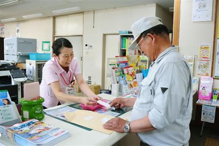 村で唯一の金融機関の平谷郵便局を利用する男性＝７月２８日、長野県下伊那郡平谷村（共同）