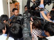 佐野研二郎氏の事務所前で対応するスタッフ（左）を取り囲む報道陣ら＝１日、東京都渋谷区（寺河内美奈撮影）