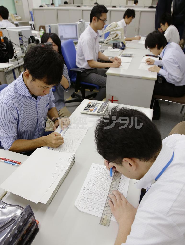 ２０１６年度予算編成に向け、農水省の担当者（右側）から概算要求データを受け取り、確認作業をする財務省の担当者＝２０１５年８月３１日午後、財務省（共同）