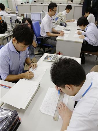 ２０１６年度予算編成に向け、農水省の担当者（右側）から概算要求データを受け取り、確認作業をする財務省の担当者＝２０１５年８月３１日午後、財務省（共同）