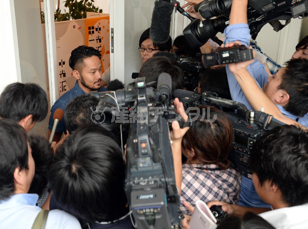 エンブレムをデザインした佐野研二郎氏の事務所前で対応するスタッフ（左）を取り囲む報道陣ら＝２０１５年９月１日、東京都渋谷区（寺河内美奈撮影）