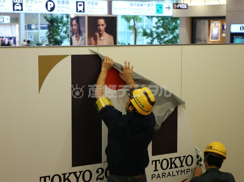 羽田空港国際線ターミナルの出口に掲げられていた佐野研二郎氏がデザインした東京五輪のエンブレムを取り外す作業員＝２０１５年９月２日午後、東京都大田区・羽田空港（古厩正樹撮影）