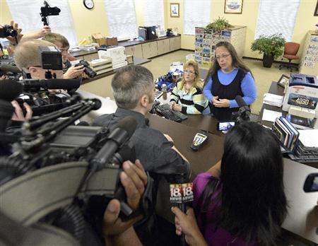 キム・デービス書記官（奥右側）に結婚許可証を発行するよう詰め寄る同性カップルのデビッド・ムーア氏（中央）＝２０１５年９月１日、米ケンタッキー州ローワン郡庁舎（ＡＰ）