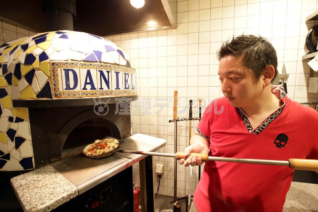 「南イタリアのようにみんなが楽しめて活気あるお店にしたい」と意気込む木澤敦・店長兼料理長。ピッツアを焼く手にも力がこもる＝２０１５年８月６日、京都市中京区（門井聡撮影）