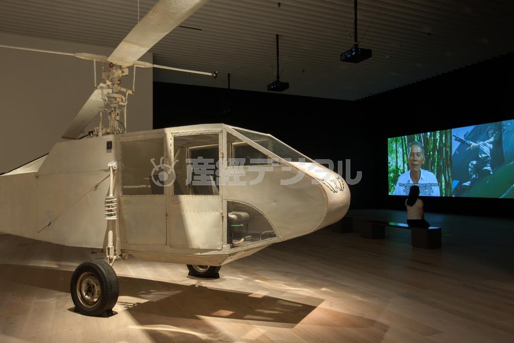 「農民とヘリコプター」（２００６年）。３チャンネル・ビデオ、カラー、サウンド、手作りの実寸大ヘリコプター。２５０×１０７０×３５０ｃｍ、１５分。Ｃｏｌｌａｂｏｒａｔｉｎｇ＿Ａｒｔｉｓｔｓ：Ｔｒａｎ＿Ｑｕｏｃ＿Ｈａｉ，Ｌｅ＿Ｖａｎ＿Ｄａｎｈ，Ｐｈｕ－Ｎａｍ＿Ｔｈｕｃ＿Ｈａ，Ｔｕａｎ＿Ａｎｄｒｅｗ＿Ｎｇｕｙｅｎ。Ｃｏｍｍｉｓｓｉｏｎｅｄ＿ｂｙ＿Ｑｕｅｅｎｓｌａｎｄ＿Ｇａｌｌｅｒｙ＿ｏｆ＿Ｍｏｄｅｒｎ＿Ａｒｔ，Ａｕｓｔｒａｌｉａ。展示風景：「ディン・Ｑ・レ展：明日への記憶」森美術館＝２０１５年（永禮賢さん撮影、森美術館提供）