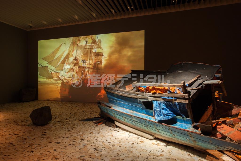 「抹消」（２０１１年）。シングルチャンネル・ビデオ、カラー、サウンド、写真、石、木製ボートの断片、木製通路、コンピューター、スキャナー、ウェブサイト（ｅｒａｓｕｒｅａｒｃｈｉｖｅ．ｎｅｔ）。サイズ可変、７分。Ｃｏｍｍｉｓｓｉｏｎｅｄ＿ｂｙ＿Ｓｈｅｒｍａｎ＿Ｃｏｎｔｅｍｐｏｒａｒｙ＿Ａｒｔ＿Ｆｏｕｎｄａｔｉｏｎ，Ｓｙｄｎｅｙ，２０１１＿Ｓｕｐｐｏｒｔｅｄ＿ｂｙ＿Ｎｉｃｈｏｌａｓ＿ａｎｄ＿Ａｎｇｅｌａ＿Ｃｕｒｔｉｓ。展示風景：「ディン・Ｑ・レ展：明日への記憶」森美術館＝２０１５年（永禮賢さん撮影、森美術館提供）