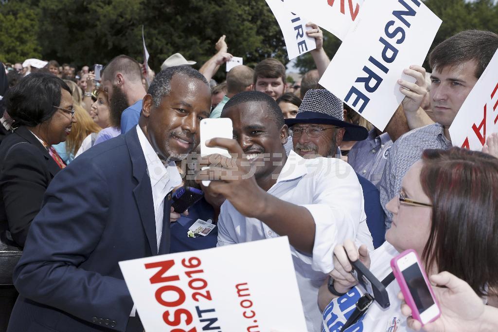 支持者の求めに応じて、一緒に写真に収まる元神経外科医のベン・カーソン氏（左）。来年の米大統領選をめぐって乱立状態の共和党候補たちの中で、支持率が２位に浮上し、「静かな台頭」ぶりをみせている＝２０１５年８月２７日、米アーカンソー州リトルロック（ＡＰ）