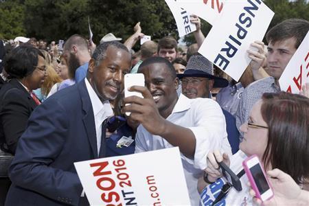 支持者の求めに応じて、一緒に写真に収まる元神経外科医のベン・カーソン氏（左）。来年の米大統領選をめぐって乱立状態の共和党候補たちの中で、支持率が２位に浮上し、「静かな台頭」ぶりをみせている＝２０１５年８月２７日、米アーカンソー州リトルロック（ＡＰ）