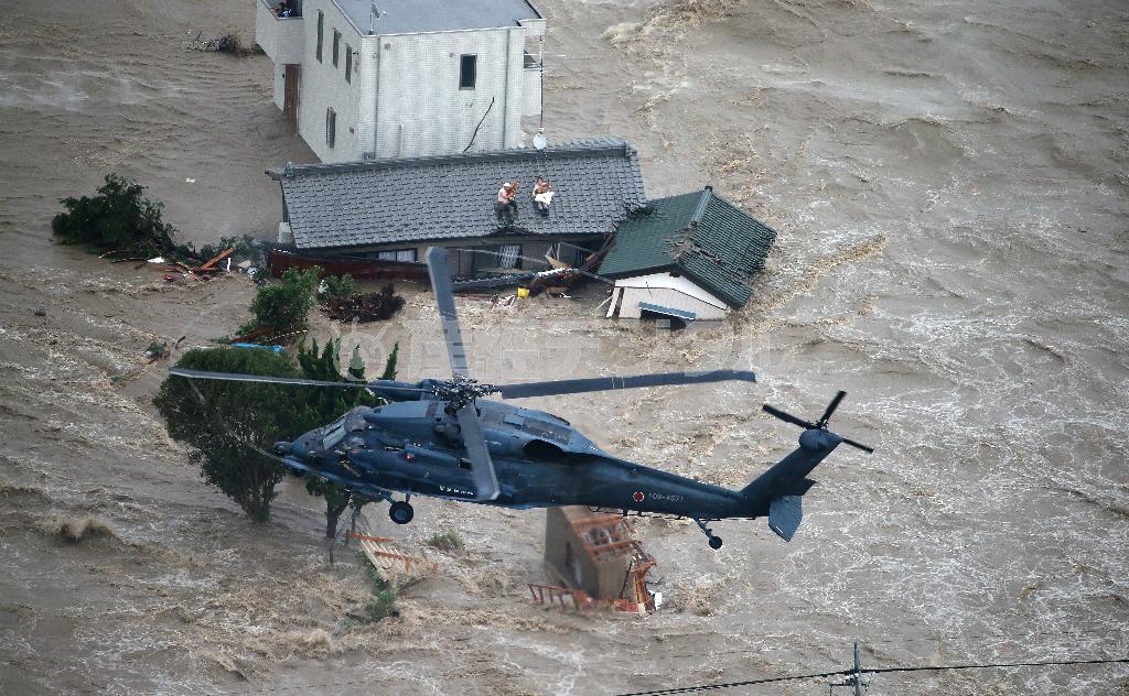 増水した鬼怒川（きぬがわ）が決壊し、屋根の上で犬を抱きながら救助を待つ住人＝２０１５年９月１０日午後、茨城県常総市（本社チャーターヘリから大山文兄撮影）