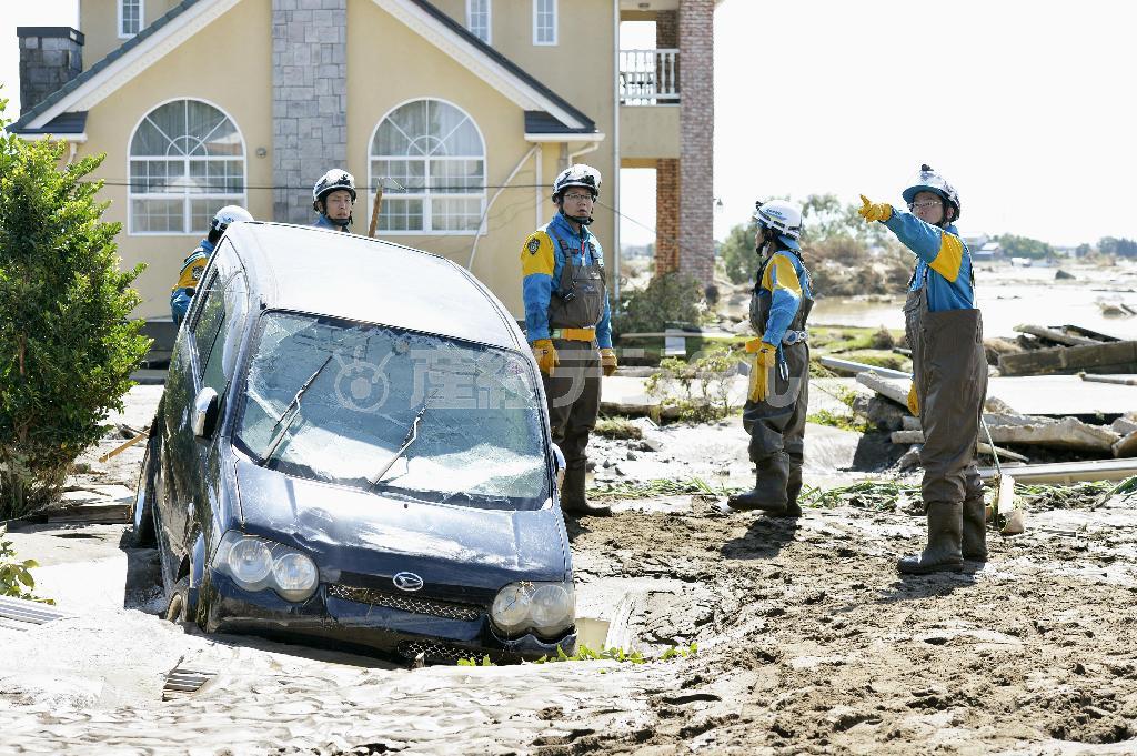 決壊した鬼怒川の堤防の周辺で行方不明者を捜索する警察官＝２０１５年９月１１日、茨城県常総市（共同）