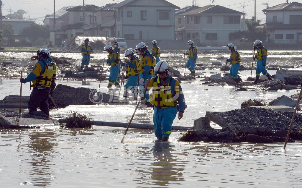 鬼怒川（きぬがわ）の決壊した堤防付近で、不明者の捜索活動を行う警察官ら＝２０１５年９月１２日、茨城県常総市（川口良介撮影）