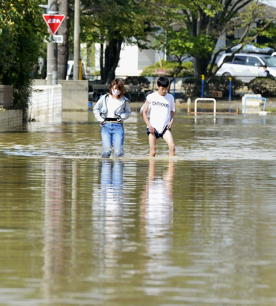 冠水したままの道路を歩く人たち＝２０１５年９月１３日午前、茨城県常総市（共同）