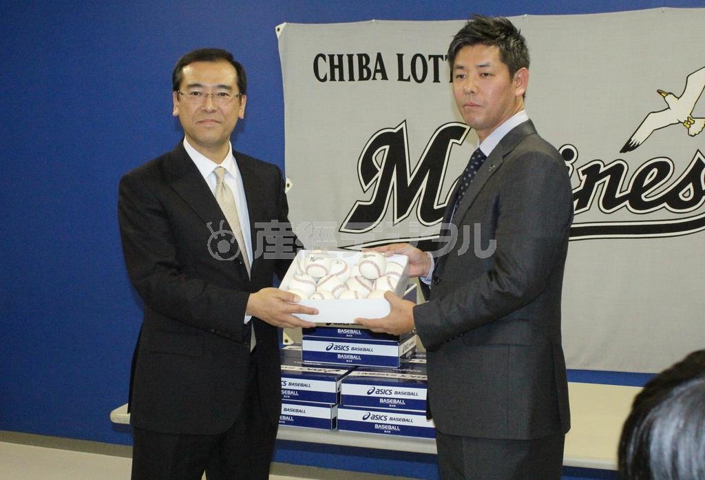 ニュージーランド野球連盟への支援発表の場で、ロッテの林信平球団本部長（左）からボールを受け取る清水直行さん＝２０１５年１月５日、千葉県千葉市美浜区のＱＶＣマリンフィールド（清水直行さん提供）