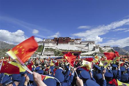 ９月８日、中国チベット自治区ラサのポタラ宮前広場で開かれた自治区成立５０年を記念する式典で、中国国旗を振る参加者ら。式典は完全に中央政府の主導で行われ、光り輝く「新チベット」が強調された＝２０１５年（ＡＰ）