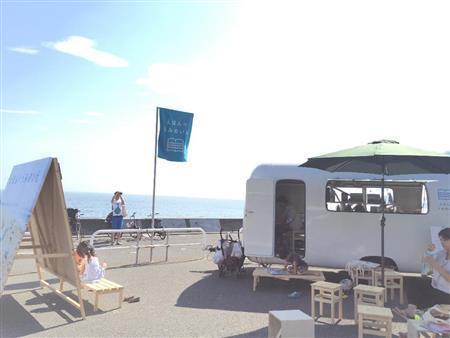 鎌倉市七里ガ浜にお目見えしたトレーラハウス「えほんのうみのいえ」で絵本を読む子供たち＝２０１５年７月２０日、神奈川県（日本財団提供）