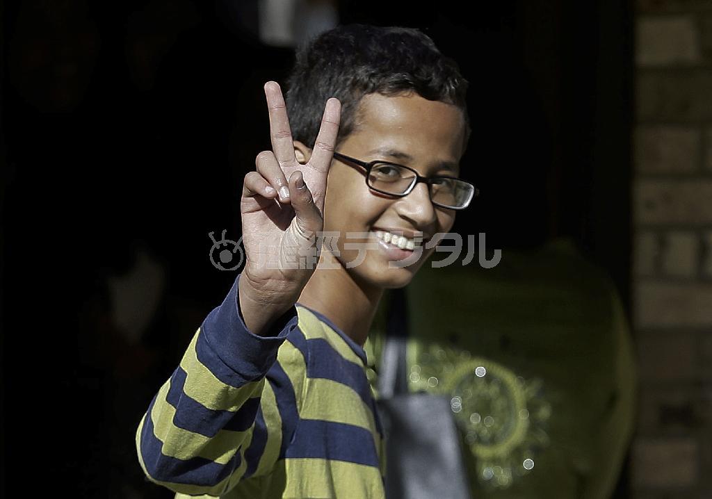 拘束を解かれ、自宅に戻り、報道陣に向かって笑顔でピースサインをするアーメド・モハメドさん。ホワイトハウスに招待されるなど、今や「時の人」だ＝２０１５年９月１７日、米テキサス州アービング（ＡＰ）