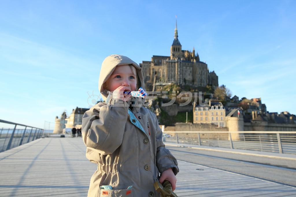 被写体と後ろの修道院が真ん中にきている“日の丸構図”ですが、この場合、被写体をシンプルに見せたいので、真ん中でもいいでしょう。一番大切なのは目の輝きや、楽しそうな表情をばっちりとらえることです＝２０１５年３月６日、フランス・モン・サン・ミッシェル（須藤夕子さん撮影）