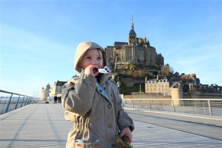 被写体と後ろの修道院が真ん中にきている“日の丸構図”ですが、この場合、被写体をシンプルに見せたいので、真ん中でもいいでしょう。一番大切なのは目の輝きや、楽しそうな表情をばっちりとらえることです＝２０１５年３月６日、フランス・モン・サン・ミッシェル（須藤夕子さん撮影）