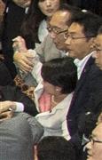 自民党の大沼瑞穂参院議員（写真中央白のスーツ）に手をかける民主党の津田弥太郎参院議員（写真中央、大沼氏の真上のグレーのスーツ）。大沼氏はこの後、写真右手奥までひきずられ、膝の上に乗せられた後に引き倒された＝１７日、参院第１委員会室（大沼事務所提供）