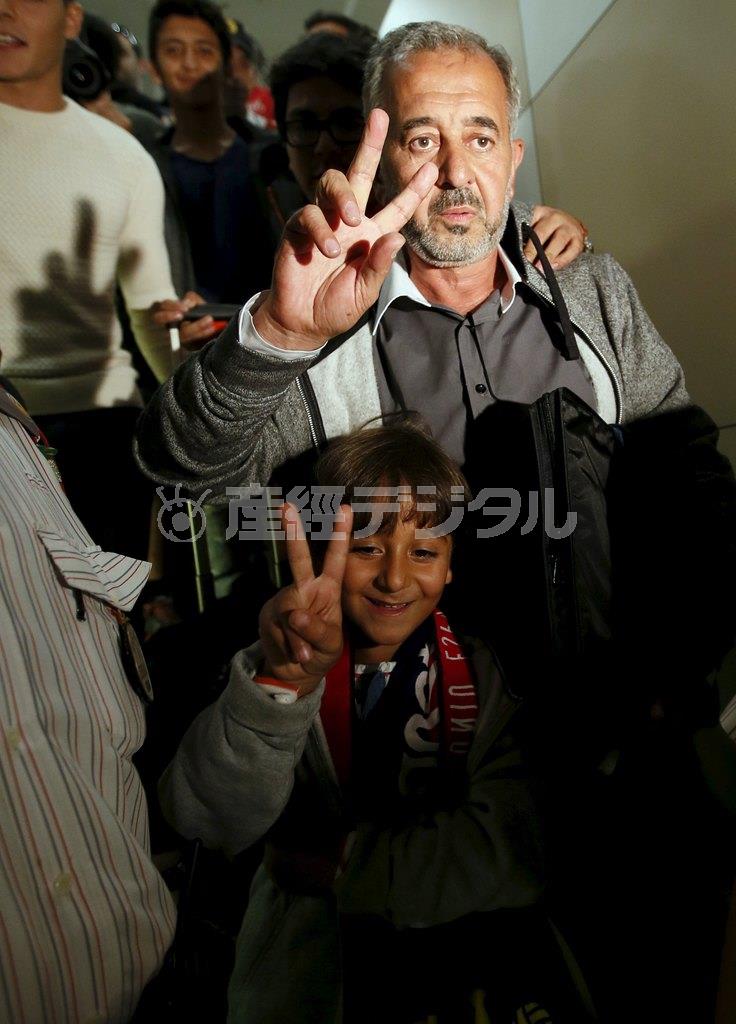 バルセロナ駅に到着したオサマ・アブドル・モフセン親子は揃ってＶサインを掲げた＝２０１５年９月１６日、スペイン・首都マドリード（ロイター）