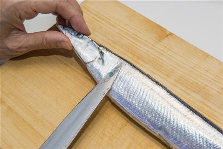 サンマの塩焼き。うろこを尻尾から頭に向かって刃先でなぜるようにして除く（松下二郎さん撮影）