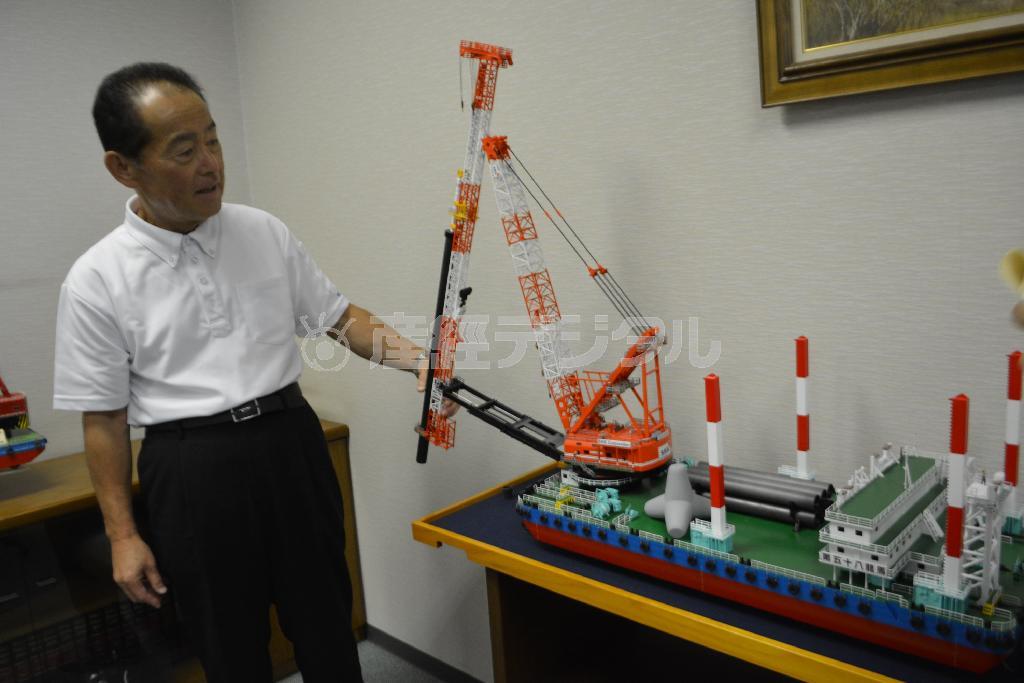 船舶用クレーンの模型を示しながら、自社の強みについて語るＳＫＫの代表取締役、牛窓正剛さん＝２０１５（平成２７）年８月２５日、高知県高知市（慶応大学、島村成撮影）
