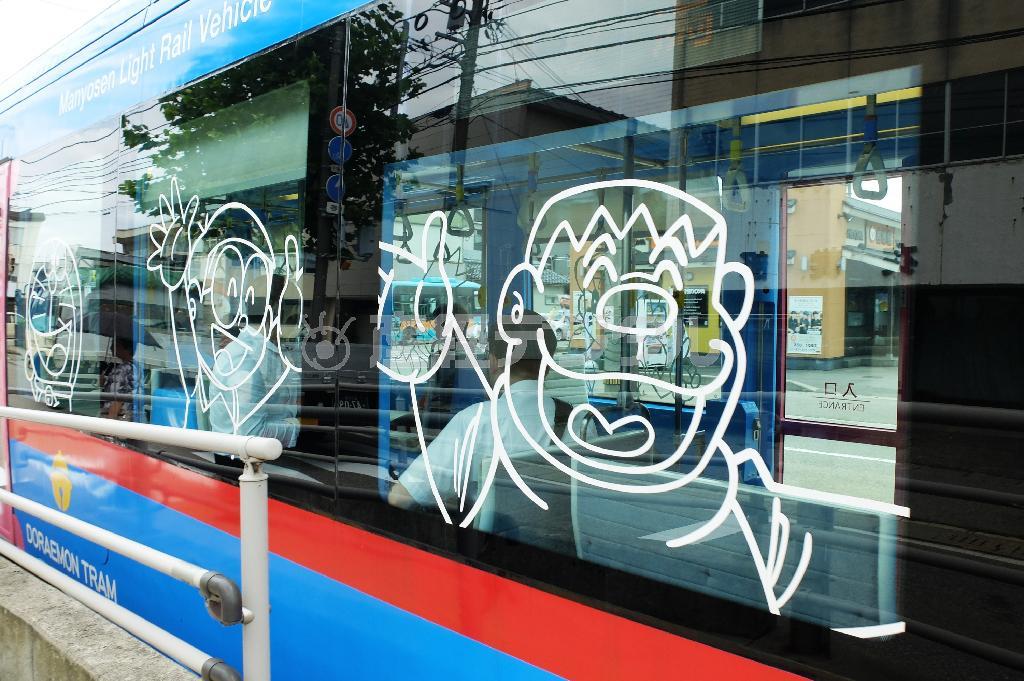 ドラえもんトラムの窓には外から見てもわかるドラえもんと仲間たちが描かれる。もちろんジャイアンも＝２０１５年７月２４日、富山県高岡市（田中幸美撮影）。（Ｃ）Ｆｕｊｉｋｏ－Ｐｒｏ