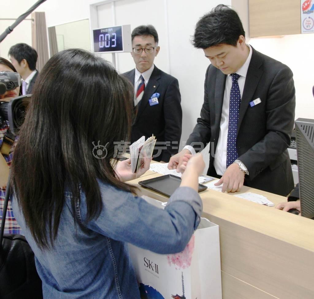 東京都中央区の松屋銀座店の専用カウンターで免税手続きを行う訪日外国人客の女性（左）＝２０１５年９月３０日（永田岳彦撮影）