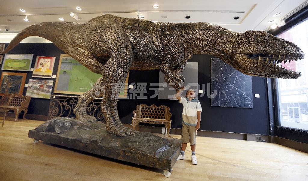 首都ロンドンのギャラリーで、恐竜時代最末期の肉食恐竜、ティラノサウルスの模型に触れて戯れる男児。ティラノサウルスは、約３００万年間、生態系の頂点に君臨したが、小惑星の地球衝突を機に姿を消していった＝２０１５年８月３日、英国（ＡＰ）