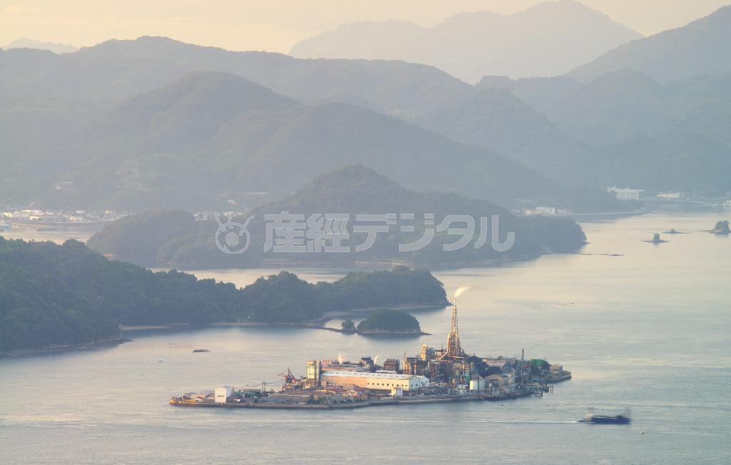 朝日を浴び、淡いオレンジ色に浮かび上がった契島（ちぎりしま）。島全体が廃墟と化した軍艦島（長崎市の端島（はしま））に対して、そのシルエットから契島は「生きた軍艦島」とも呼ばれる＝２０１５年９月５日、広島県竹原市の朝日山から（川口良介撮影）