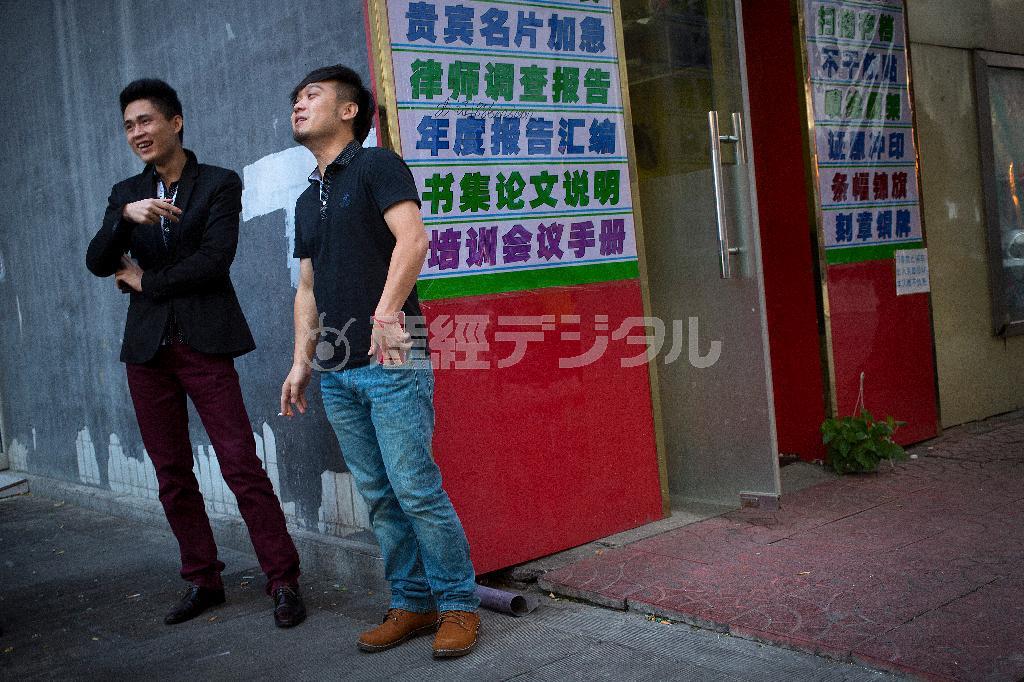 オフィスビルの外でたばこを吸う男性＝２０１５年１０月８日、中国・首都北京市（ＡＰ）