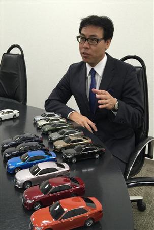 「クラウン」のミニカーを前にインタビューに答えるトヨタ自動車の秋山晃チーフエンジニア＝東京都内