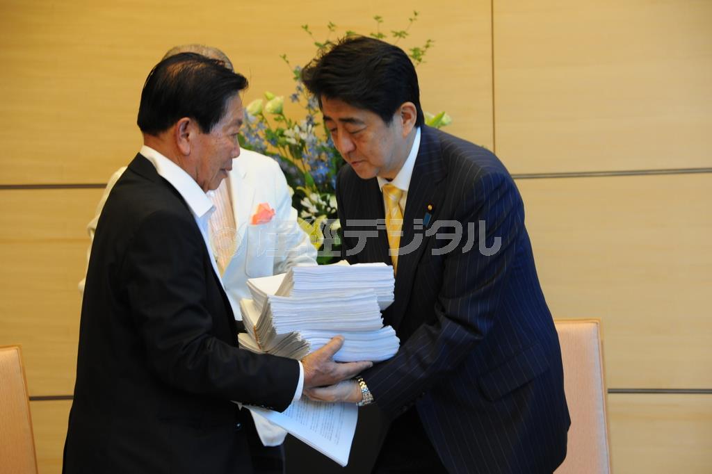 安倍晋三（しんぞう）首相（右）に、署名を渡す訪日団長で前フィリピン日系人会連合会会長のカルロス寺岡氏＝２０１５年７月２２日（日本財団提供）