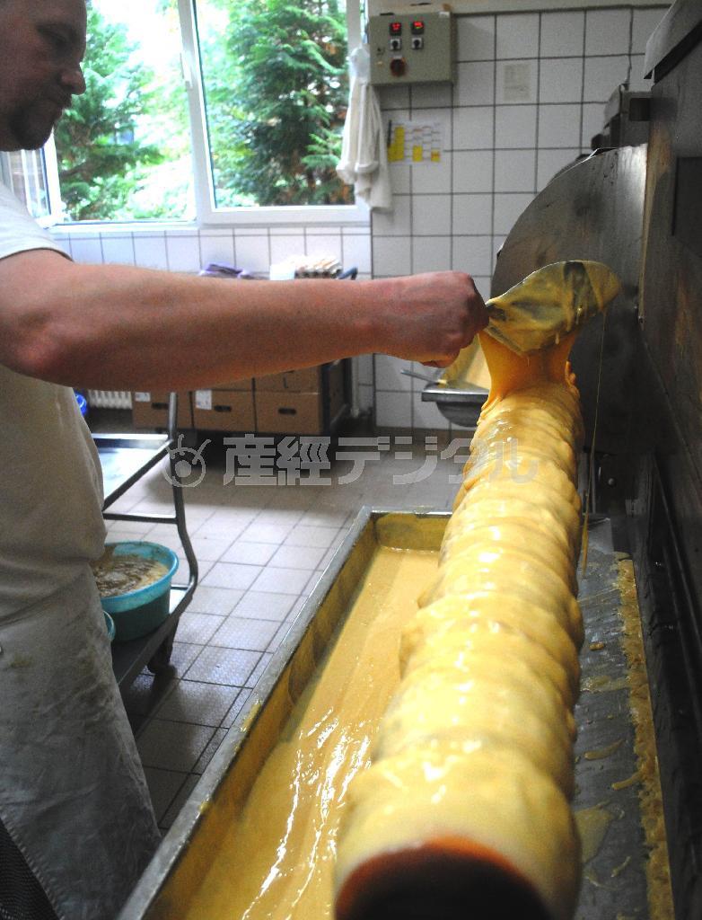 心棒の周りに焼けた生地の上から、さらに生地をかける職人。この工程を何度も繰り返す＝２０１５年１０月２０日、ドイツ・首都ベルリン（宮下日出男撮影）