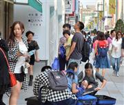 路上に座り込み、買い込んだ商品をスーツケースに詰め込む中国人旅行客。こういった姿もすでに珍しくなくなったが、訪日中国人は健康面でも日本に興味を示している＝１０月４日、東京・銀座の中央通り