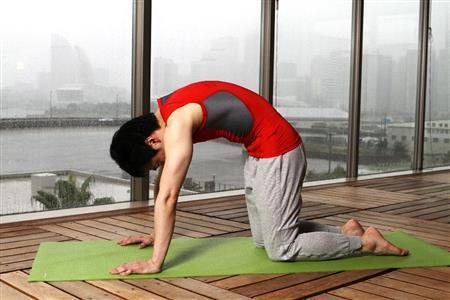 ネコのポーズ（２）。次に、息を吐きながら視線を床からおなかの方へ向け、肩甲骨を左右に広げるように首から腰にかけて丸める＝２０１５年９月１７日、神奈川県横浜市神奈川区のインスパ横浜（田中幸美撮影）