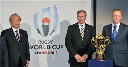 ロゴマークの前で記念撮影に応じる（左から）日本大会組織委の嶋津昭事務総長、ワールドラグビーのブレット・ゴスパー最高経営責任者（ＣＥＯ）、アラン・ギルピンＷ杯統括責任者＝２０１５年１０月２７日、英国・首都ロンドン（共同）