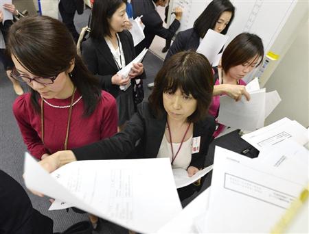 中間決算の発表がピークを迎え、資料を配布する企業の担当者＝３０日午後、東京・日本橋兜町の東京証券取引所