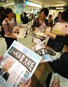 大村智・北里大特別栄誉教授のノーベル医学・生理学賞受賞を伝える本紙号外を受け取る人々＝大阪市北区のＪＲ大阪駅前（恵守乾撮影）