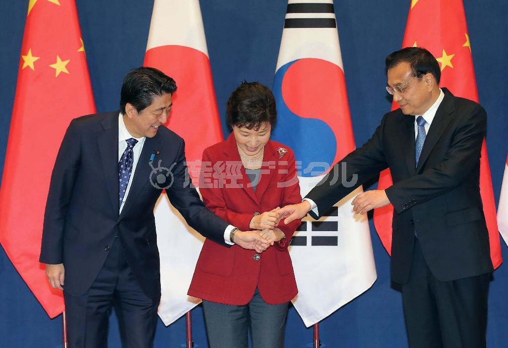 ３カ国首脳会談を前に、韓国の朴槿恵（パク・クネ）大統領（中央）に促され、安倍晋三（しんぞう）首相（左）と中国の李克強首相の３人で手を重ねた＝２０１５年１１月１日、韓国・首都ソウルの青瓦台（ＡＰ）