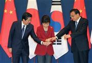 ３カ国首脳会談を前に、韓国の朴槿恵（パク・クネ）大統領（中央）に促され、安倍晋三（しんぞう）首相（左）と中国の李克強首相の３人で手を重ねた＝２０１５年１１月１日、韓国・首都ソウルの青瓦台（ＡＰ）