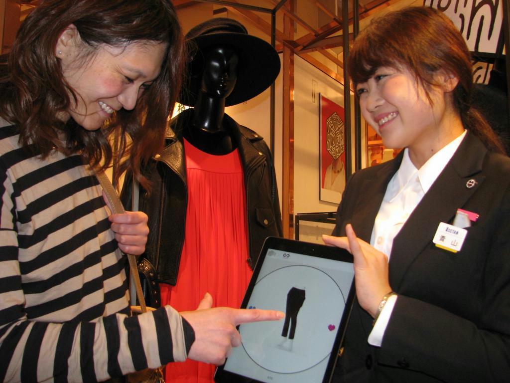 店員が持つタブレットに表示された洋服を指で指す買い物客＝東京都新宿区の伊勢丹新宿本店