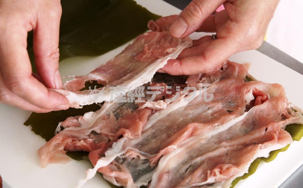 豚肉のコンブ巻き（作り方１）＿＿コンブを広げ、まんべんなく広げた豚肉をのせて巻き、かんぴょうで結ぶ（田中幸美撮影）