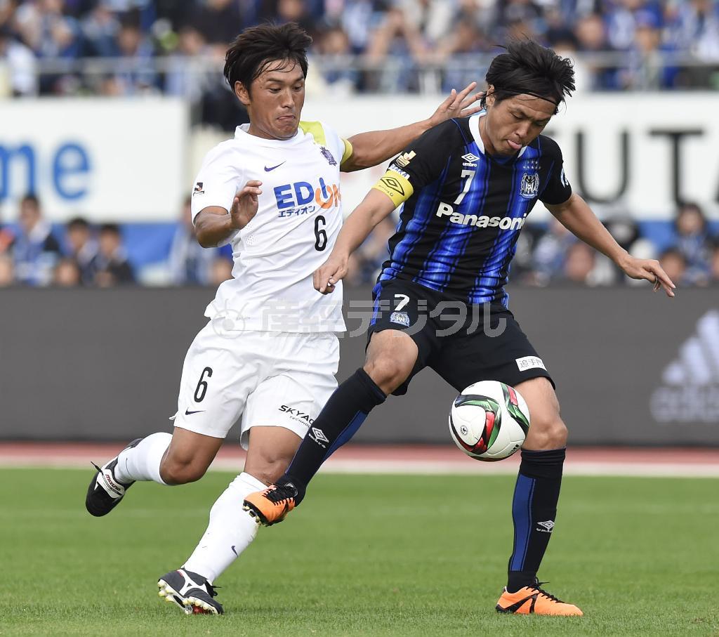 前半、競り合うＧ大阪・遠藤保仁（やすひと、右）と広島・青山敏弘＝２０１５年１１月７日、大阪府吹田市の万博記念公園競技場（甘利慈撮影）