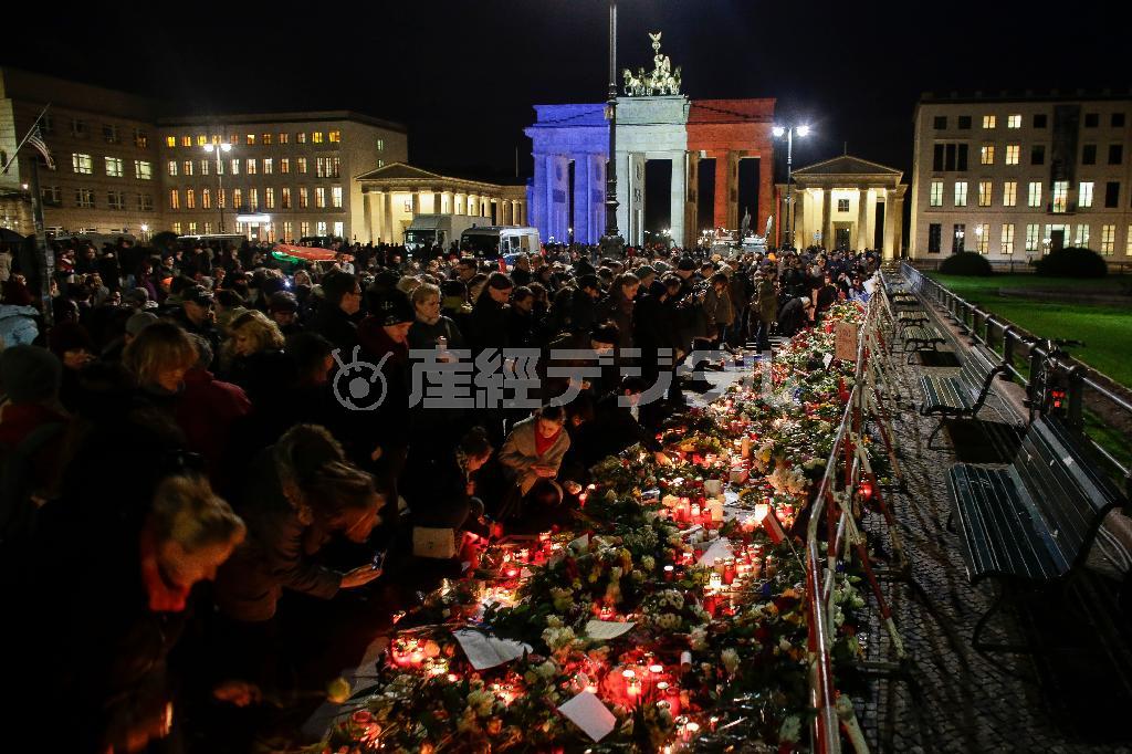 フランス国旗の色にライトアップされた首都ベルリンのブランデンブルク門でテロの犠牲者を追悼する市民ら。世界中のモニュメントがライトアップされた＝２０１５年１１月１４日、ドイツ（ＡＰ）