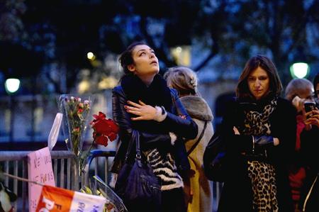 同時多発テロで襲撃され、花束などが供えられたバタクラン劇場付近で胸に手を当てる女性＝１４日、パリ（ゲッティ＝共同）