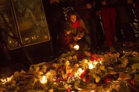 銃撃されたパリの飲食店前でキャンドルをともして追悼する親子＝１４日（ＡＰ）