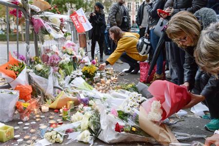テロで観客ら８０人以上が犠牲になったパリのバタクラン劇場近くで花束を供える人々＝１４日（共同）