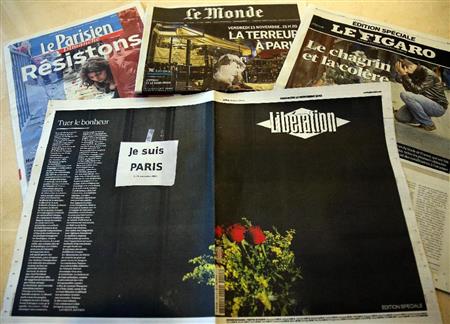 パリ同時多発テロを報じる地元紙。中央のリべラシオン紙は黒塗りの見開きに花束だけの紙面で報じた＝１５日、フランス・パリ（大西正純撮影）